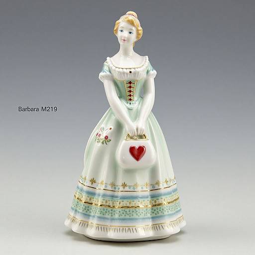 Photograph of a porcelain doll in a white, ornate ball gown with gold and blue trim, holding a heart-shaped ornament, with 
