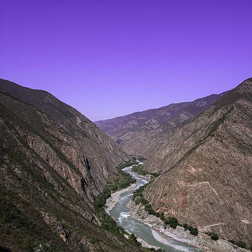 Photograph of a narrow, rocky canyon with a winding river, surrounded by steep, brown mountains under a vivid, clear blue sky.