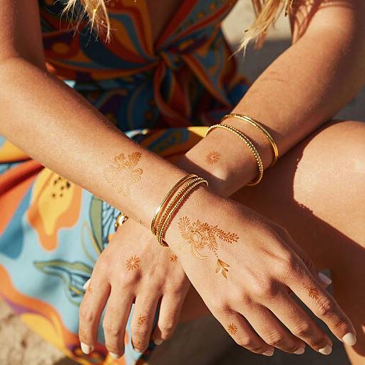 Close-up of woman's hands with gold bracelets and henna tattoos