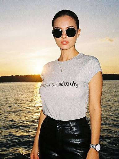 Photograph of a woman with dark hair in a bun, wearing sunglasses, white 