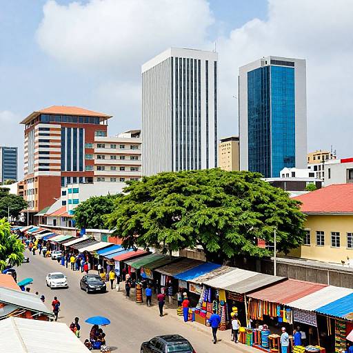 Photograph of a bustling urban street market with colorful stalls, tall modern buildings, and lush green trees under a partly cloudy sky.