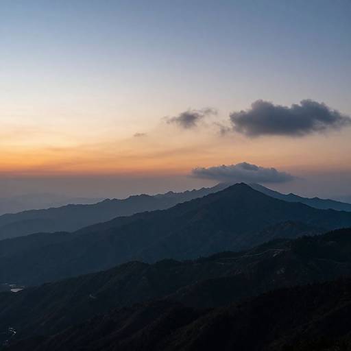 Photograph of a serene mountain landscape at dusk, with a gradient sky from orange to blue, silhouetted mountains, and a single dark cloud