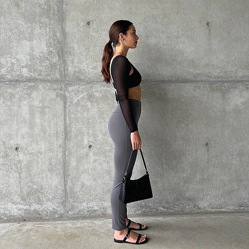 Woman in urban casual outfit standing against concrete wall