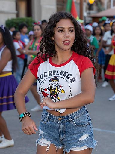 Photograph of a young Latina woman with curly black hair, wearing a red and white 
