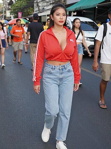 Photograph of an Asian woman with medium brown skin, black hair, red zip-up top, blue high-waisted jeans, white sneakers, walking
