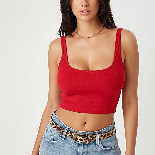 Photograph of a young woman with medium brown skin, black shoulder-length hair, wearing a red ribbed tank top, leopard print belt, and blue