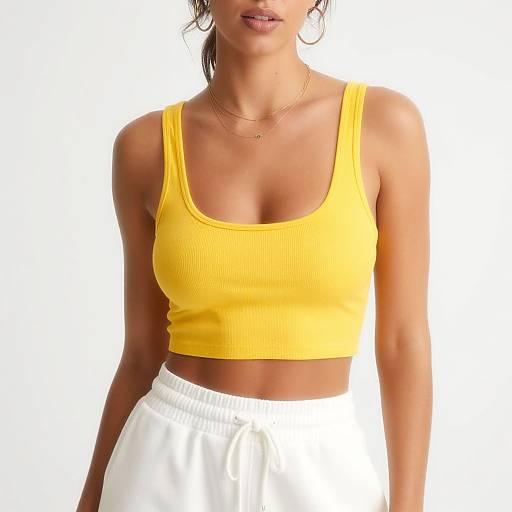 Photograph of a woman with tan skin wearing a bright yellow ribbed tank top and white drawstring pants, with her face partially visible.