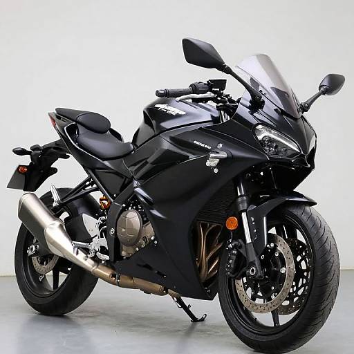 Photograph of a sleek, black Kawasaki sport motorcycle with silver exhaust, large front windshield, and black tires, standing on a white background.