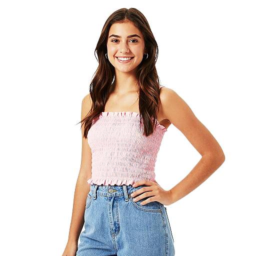 Photograph of a smiling young woman with long dark hair, wearing a white, ribbed, sleeveless top and high-waisted blue jeans,