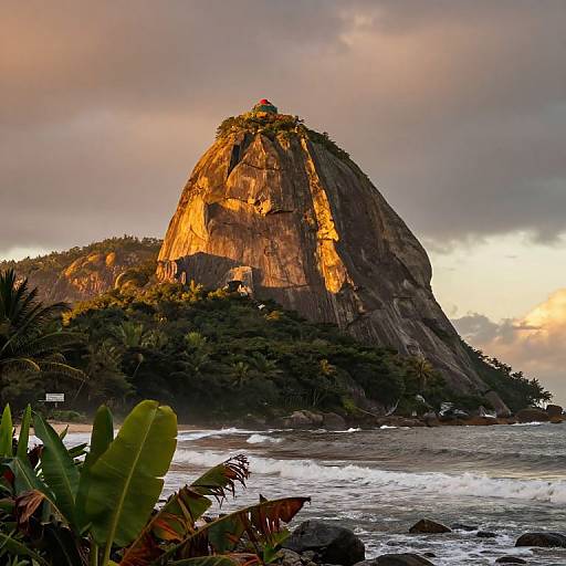 Photograph of a towering, sunlit rock formation with lush greenery at its base, surrounded by ocean waves and tropical plants, under a dramatic,