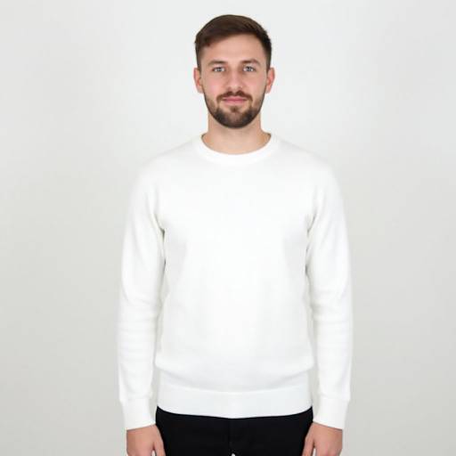 Photograph of a bearded Caucasian man with short brown hair, wearing a plain white long-sleeve shirt and black pants, standing against a plain