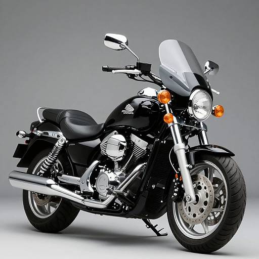 Photograph of a sleek, black Harley-Davidson motorcycle with chrome accents, large windshield, orange headlights, and silver wheels, set against a gray