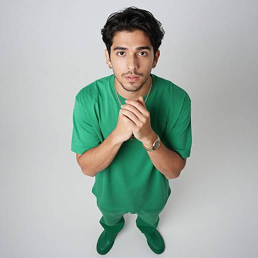 Photograph of a young man with medium skin tone, black hair, and brown eyes, wearing green scrubs, standing against a white background, looking
