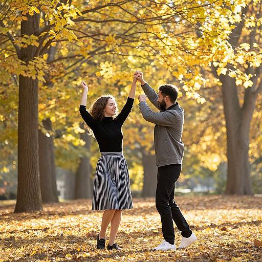 Photograph of a couple dancing in a sunlit autumn park, with golden leaves, holding hands, wearing black and white striped skirt, black sweater,