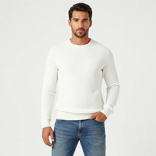 Photograph of a handsome, bearded man with short dark hair, wearing a white knit sweater and blue jeans, standing against a plain white background.