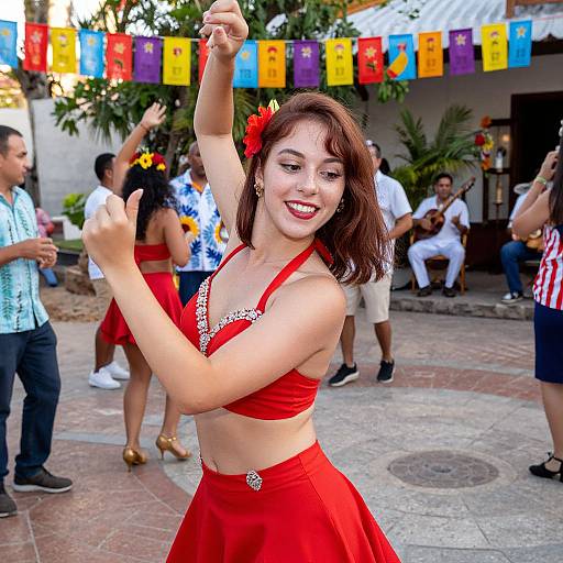 Photograph of a smiling young woman with fair skin, brown hair, red dress, and flower, dancing outdoors among people, colorful flags, and tropical