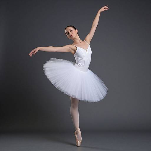 Photograph of a graceful ballerina in a white tutu, pink pointe shoes, and black bun, posing elegantly against a dark gray
