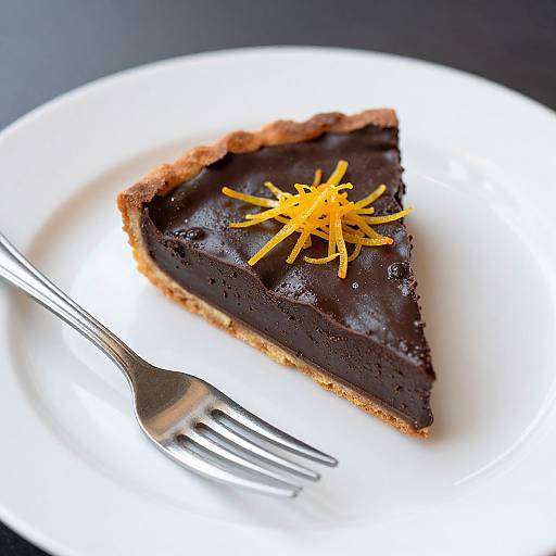 Photograph of a single slice of rich, dark chocolate pie with a golden-yellow shredded topping, on a white plate with a silver fork to the left