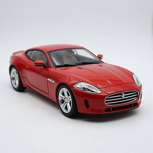 Photograph of a sleek, red, two-door sports car with silver wheels and a black grille, set against a white background.