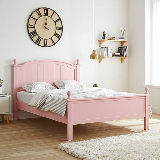 Photograph of a bright, minimalist bedroom with a pink wooden bed, white striped pillows, large clock on white wall, wooden floor, and white sh