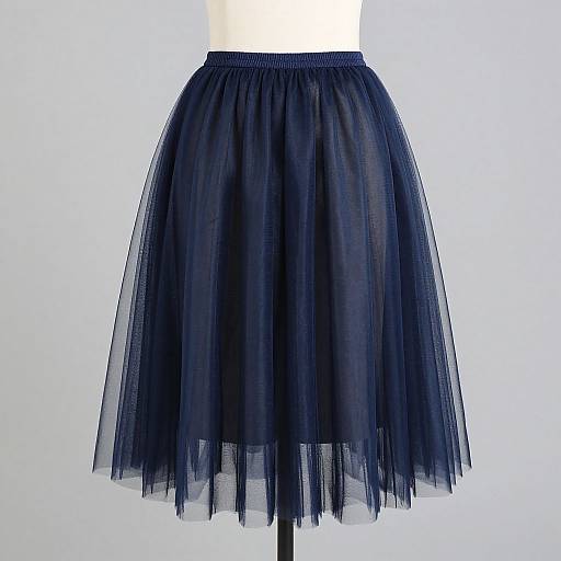 Photograph of a dark blue, sheer, pleated tulle skirt on a white mannequin, centered against a plain light background.