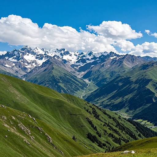 Photograph of a vivid mountain landscape with green slopes, snow-capped peaks, and a bright blue sky with fluffy white clouds.