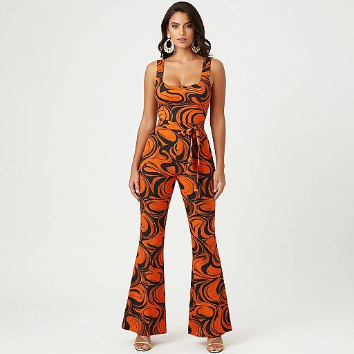 Photograph of a young woman with medium brown skin and black hair wearing an orange and black swirl-patterned, sleeveless jumpsuit with wide legs,