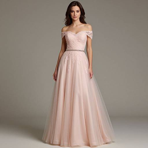 Photograph of a young woman with wavy brown hair wearing an off-shoulder, pale pink, lace and tulle ball gown, standing against