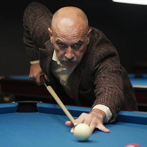 Photograph of an intense elderly bald man with a mustache, wearing a brown tweed suit, aiming a pool cue at a white ball on a