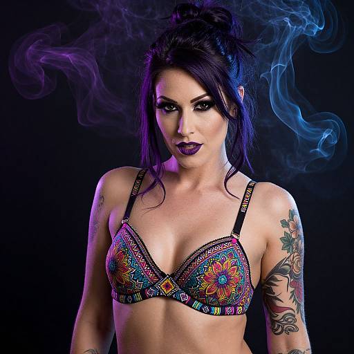 Photograph of a tattooed woman with dark hair, purple lipstick, wearing a colorful, floral-patterned bra against a black background with blue smoke.