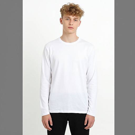 Photograph of a young, fair-skinned, curly-haired boy with blue eyes, wearing a plain white long-sleeve shirt and black pants,