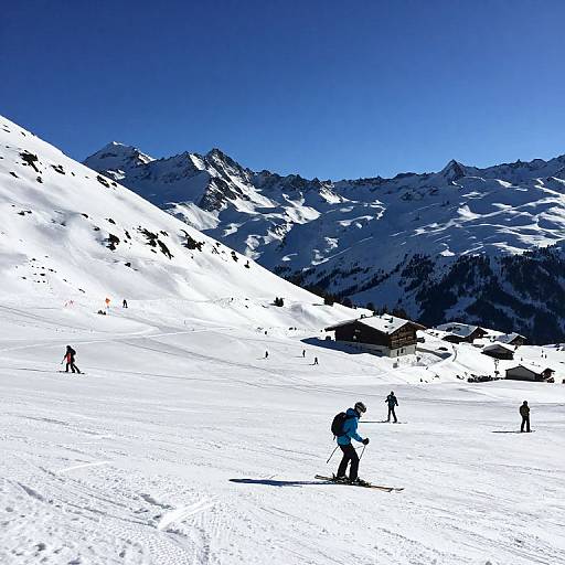 Photograph of a snowy mountain landscape with skiers in silhouette, bright blue sky, and dark, jagged peaks in the background.