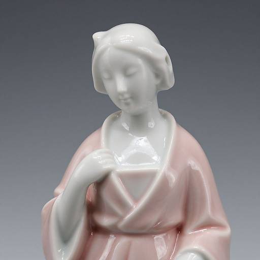 Photograph of a white ceramic statue with soft pink robe, delicate features, and gentle expression, set against a gradient blue background.
