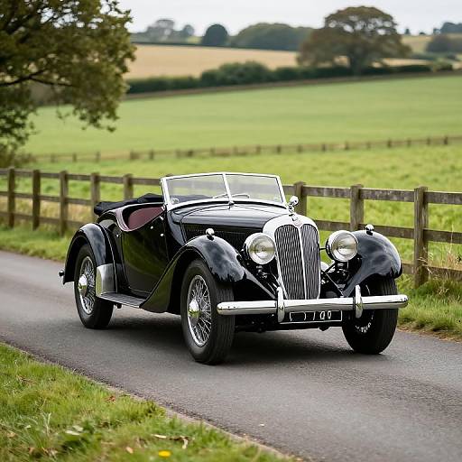 Photograph of a sleek, black vintage convertible car with chrome accents driving on a rural road, surrounded by green fields and wooden fences.