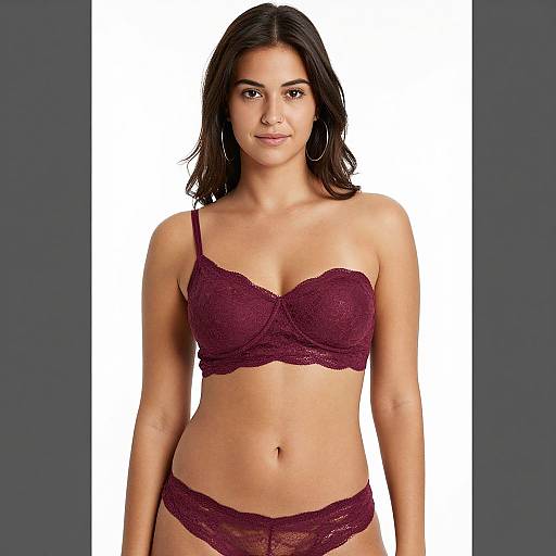 Photograph of a young woman with medium skin tone, black hair, wearing a maroon lace bra and matching panties, standing against a white and dark