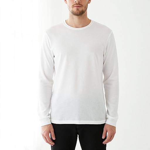 Photograph of a bearded man wearing a plain white long-sleeve shirt and black pants, standing against a white background.