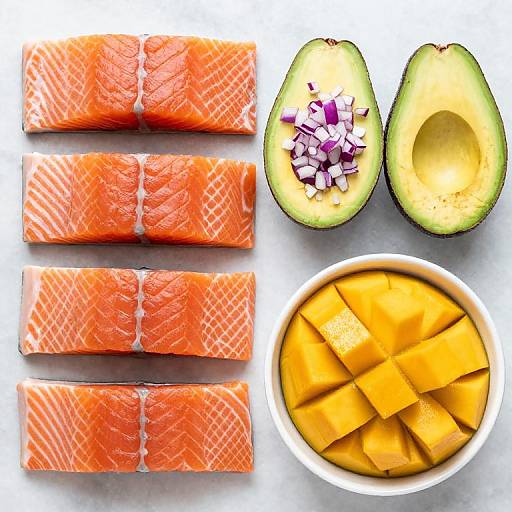 Photograph of vibrant ingredients: four bright orange salmon slices, two halved avocados with diced red onions, and a bowl of yellow mango cubes