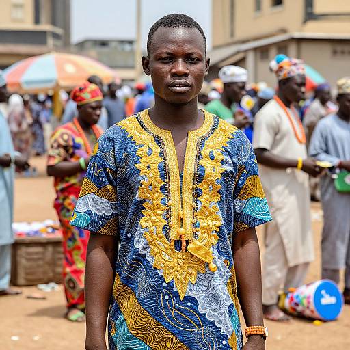 Photograph of a young African woman with dark skin, wearing a colorful blue and yellow embroidered dress, standing in a bustling outdoor market with blurred, colorful