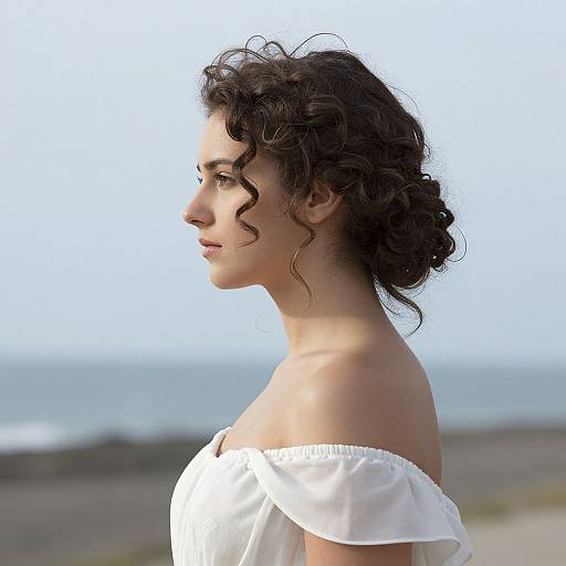 Photograph of a young woman with curly dark hair, fair skin, and delicate features, wearing an off-shoulder white dress, profile view,
