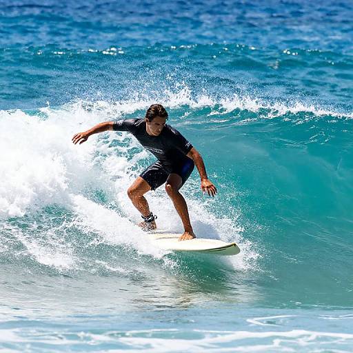 Photograph of a male surfer in a black wetsuit riding a vibrant blue ocean wave, with foamy white water splashing around him.