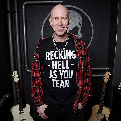 Photograph of bald middle-aged man with fair skin, smiling, wearing red plaid shirt, black 