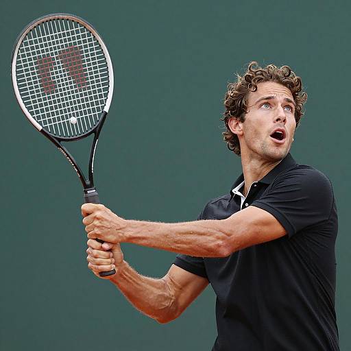 Tennis player mid-swing with black polo