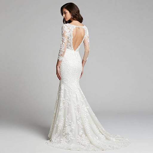 Photograph of a brunette woman in a white, lace, long-sleeve, backless wedding dress with a fitted, mermaid-style skirt,