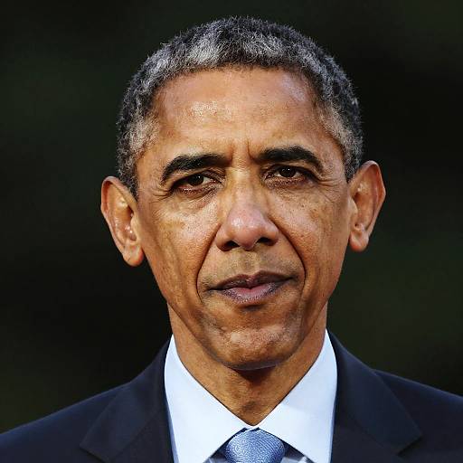 Photograph of an older Middle Eastern man with short, graying black hair, wearing a black suit, white shirt, and blue tie, against a