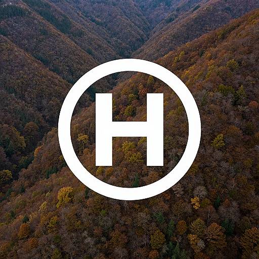 Aerial photograph of a forested mountain landscape with a large white circular logo containing a bold white 