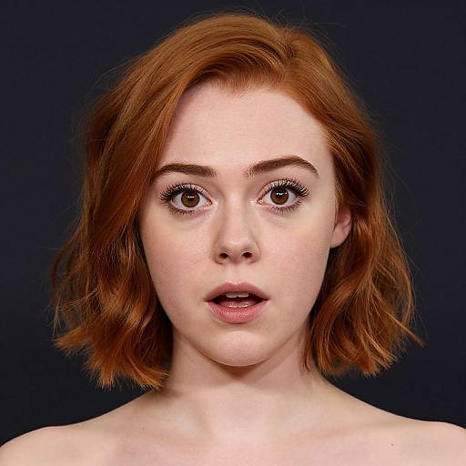 Photograph of a fair-skinned, red-haired woman with wide brown eyes, slightly parted lips, and subtle freckles, against a dark blue