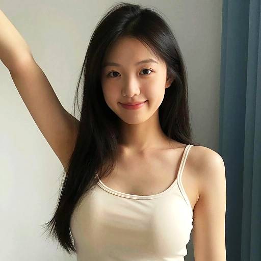 Photograph of a young Asian woman with long black hair, wearing a white tank top, smiling, arm raised, standing against a light gray wall and