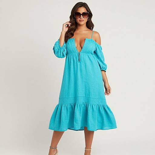 Photograph of a brunette woman in a bright blue off-shoulder, V-neck, knee-length dress with a ruffled hem, wearing sunglasses and