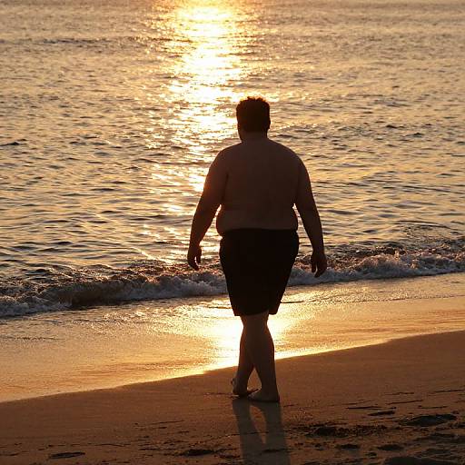 Silhouetted person walking on beach at sunset, golden sunlight reflecting on water, gentle waves, sand in foreground, serene ocean scene.