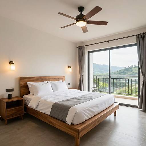 Modern bedroom photograph: wooden bed with white and gray linens, two bedside tables, ceiling fan, large window with mountain view, gray curtains.